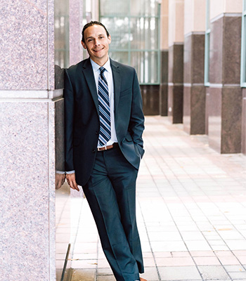 Image of attorney Adam R. Farkas outdoors leaning against a wall