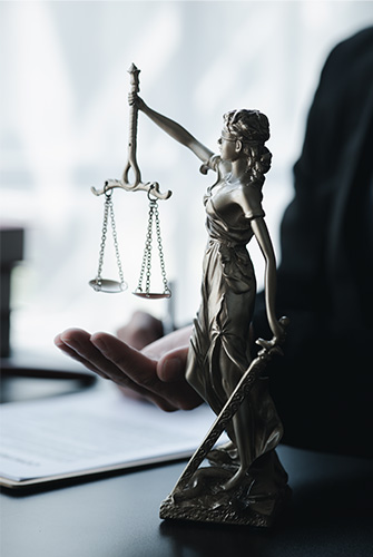 Lady Justice holding scales on desk with hand image in background referencing Criminal Case