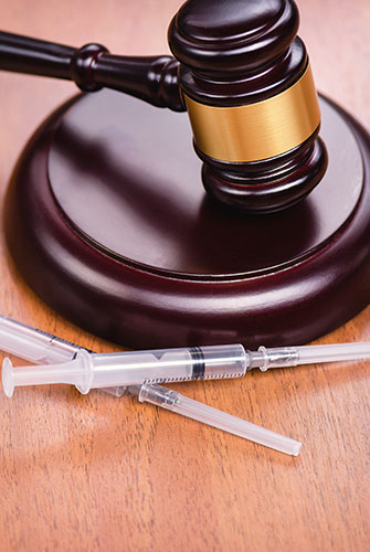 Gavel image with syringes beside it regarding Drug Crime