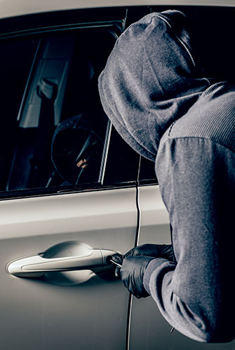 Man in hoodie breaking into a car for Felony Law page
