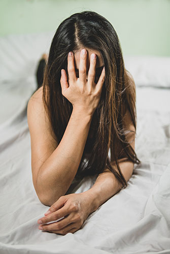 Image of lady on bed holding hand to her face for Sex Crimes page