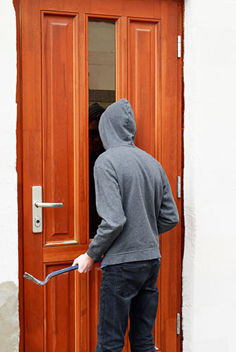 Image of a person at a door with a crow bar representing Theft